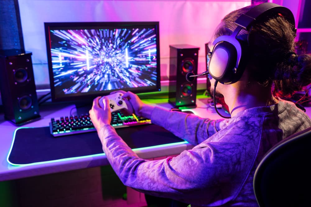 Gamer concentré devant son Moniteur PC affichant des graphismes de jeu lumineux.