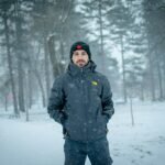 man in black jacket standing on snow covered ground