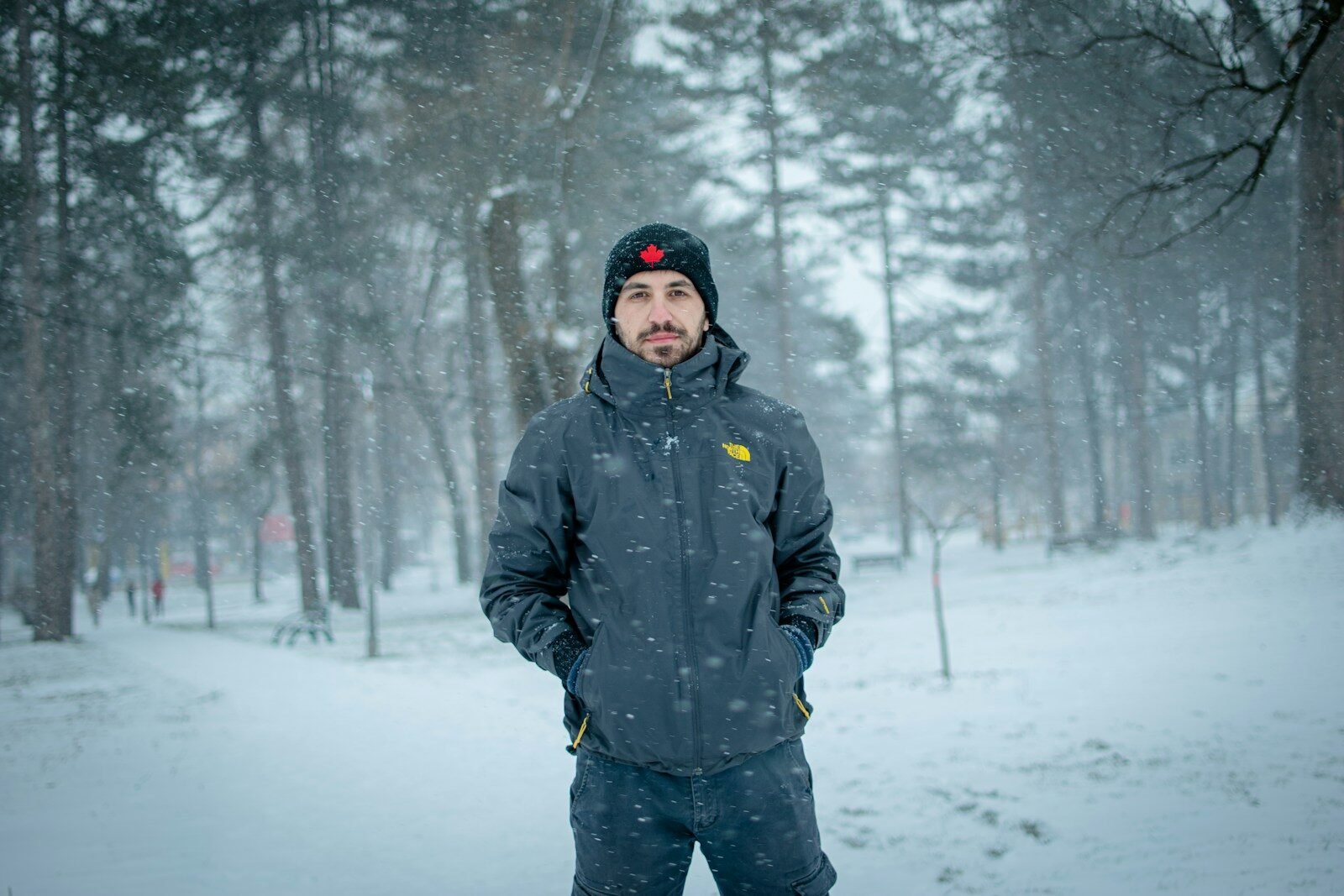man in black jacket standing on snow covered ground